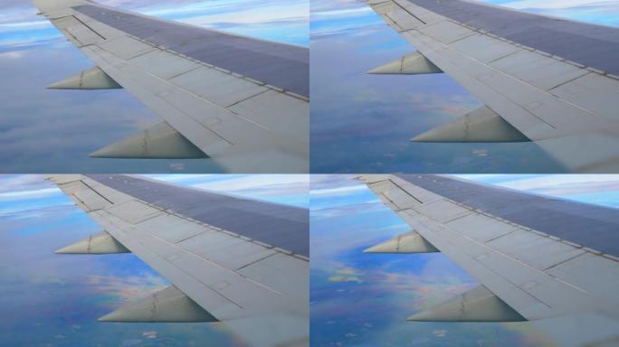 飞机机翼的飞机飞行视图。乘飞机旅行。乘飞机出差。在飞机的机翼下，云层和陆地与湖泊飞逝