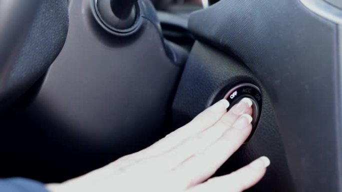 女人手指按下汽车的发动机启动停止按钮