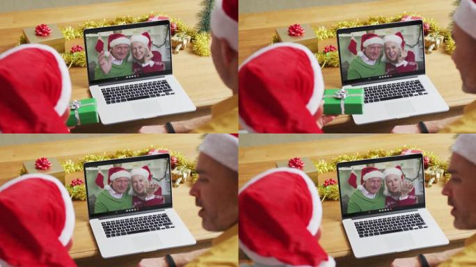 带有圣诞老人帽子的高加索父子使用笔记本电脑进行圣诞节视频通话，屏幕上有情侣