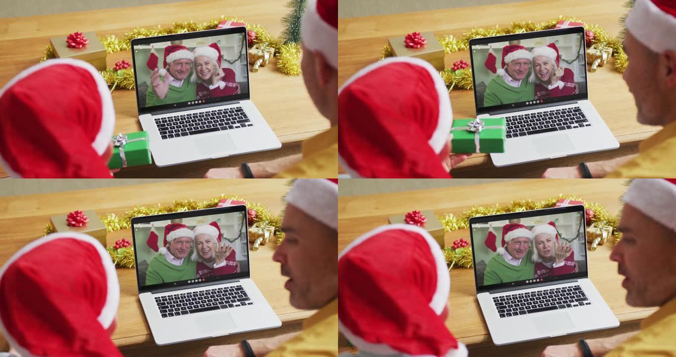 带有圣诞老人帽子的高加索父子使用笔记本电脑进行圣诞节视频通话，屏幕上有情侣