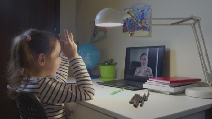 可爱的高加索学龄前女孩，一个带着老师在笔记本电脑上在线学习字母的孩子，在线远程学习，在家中的虚拟视频
