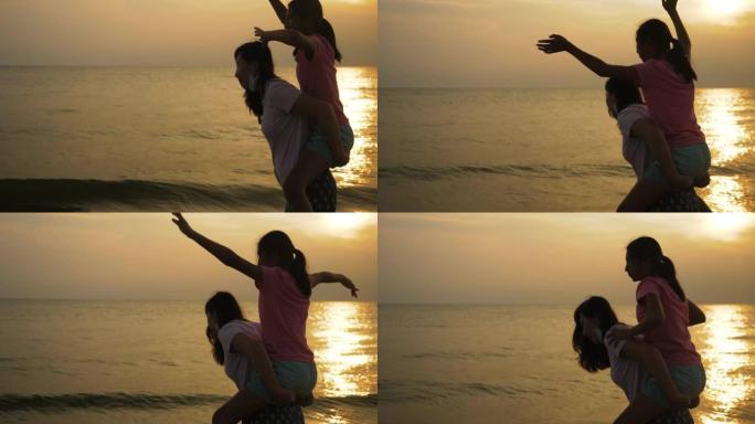 女孩背着母亲在海滩上的日出背景，生活方式概念。