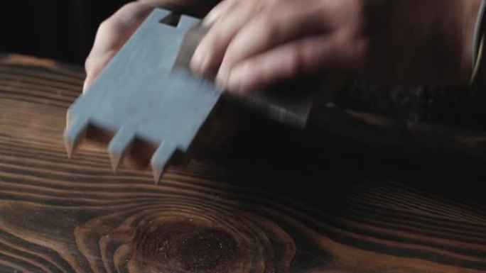 木匠用燕尾榫磨碎了一个涂漆的木零件。自制牛奶木材涂料。木工概念。工匠研磨木制品，同时鼓励砂纸