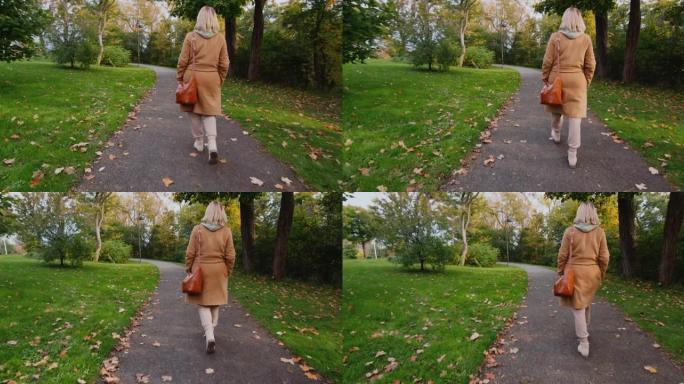 一个穿着外套的女人带着包在秋天的公园里散步，后视