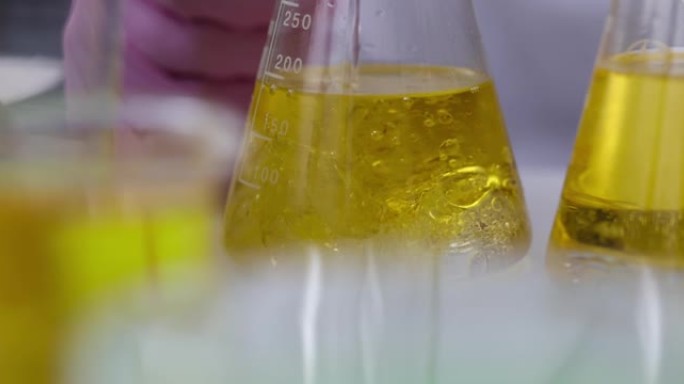 科学家化学家在实验室特写4k电影慢动作中，用机油将液体倒入烧瓶中