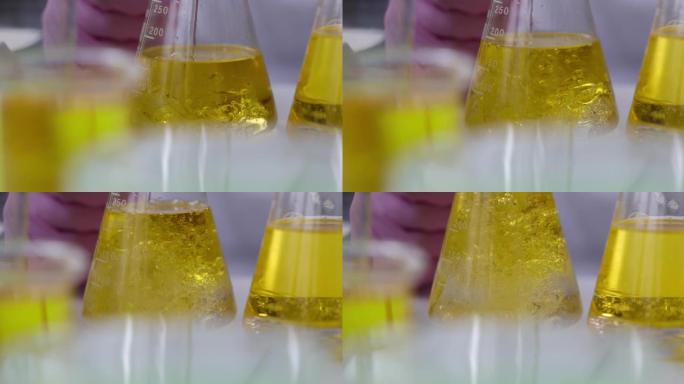 科学家化学家在实验室特写4k电影慢动作中，用机油将液体倒入烧瓶中