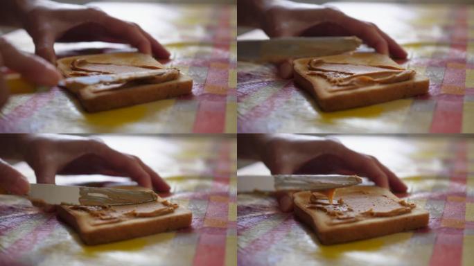 花生酱。用花生酱慢动作制作三明治的女性手。桌子上的面包和花生酱特写。
