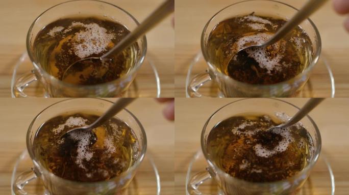 一杯新鲜冲泡的红茶充分搅拌糖，放在木制桌子上，逸出蒸汽，温暖柔和。透明玻璃杯中新鲜酿造的红茶。下午茶