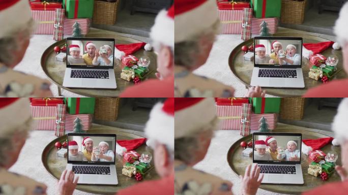 戴着圣诞老人帽子的白人高级夫妇使用笔记本电脑与家人在屏幕上进行圣诞节视频通话