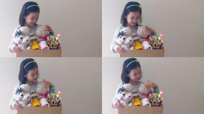 混合亚洲青年志愿者女孩拿着装满旧玩具、衣服、书籍和文具的盒子捐赠快乐慈善、亚洲社区