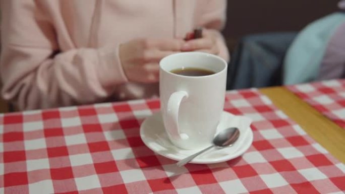 女人将白糖或甜叶菊倒入一杯茶中