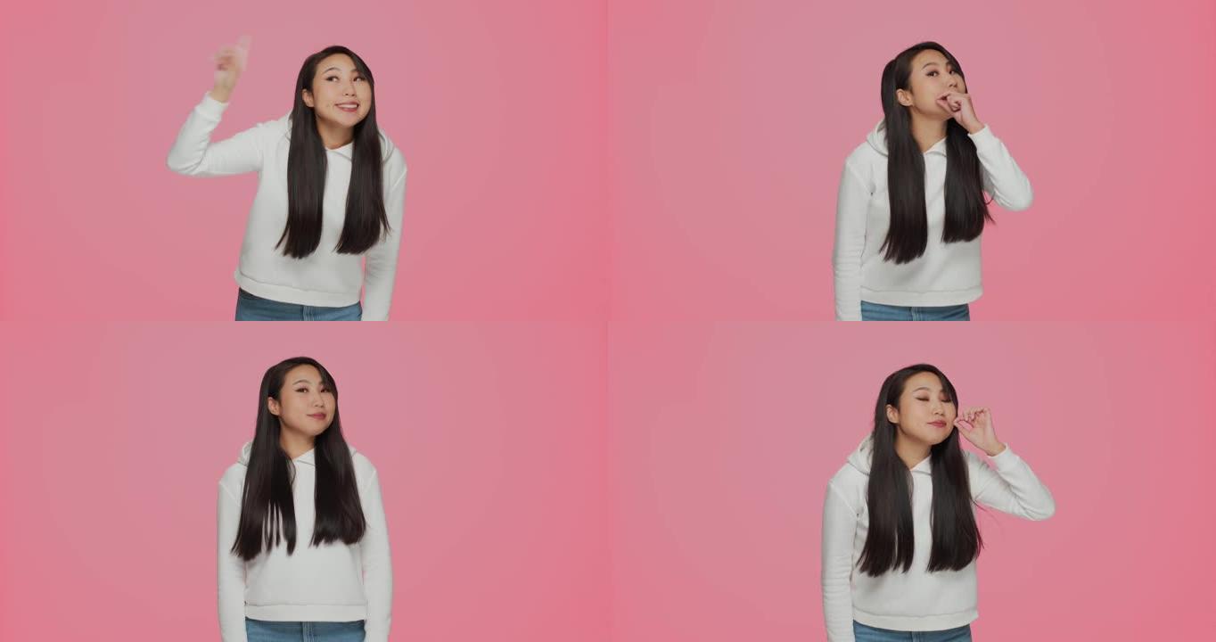 沉默手势。可爱的现代亚洲年轻女孩展示沉默承诺在粉色工作室背景上保密