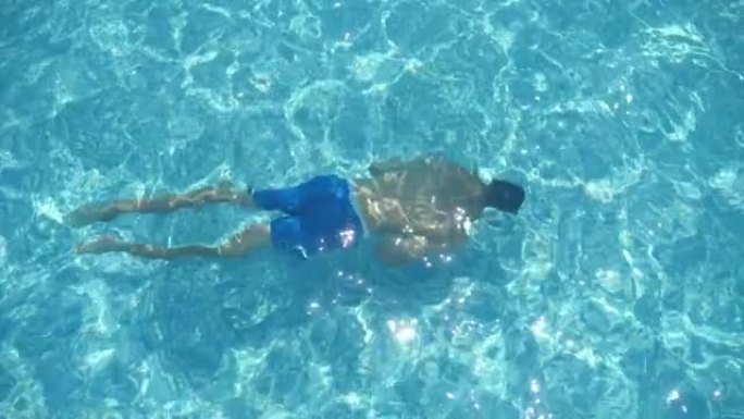 穿着短裤的黑发男人夏天在slo-mo的水下游泳池游泳
