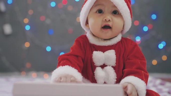 圣诞节那天，穿着圣诞老人服装的女婴坐在家里的地板上。