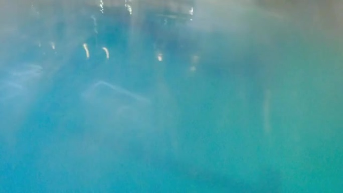 室内训练池中的年轻大胡子男子-在水中潜水并在水下游泳