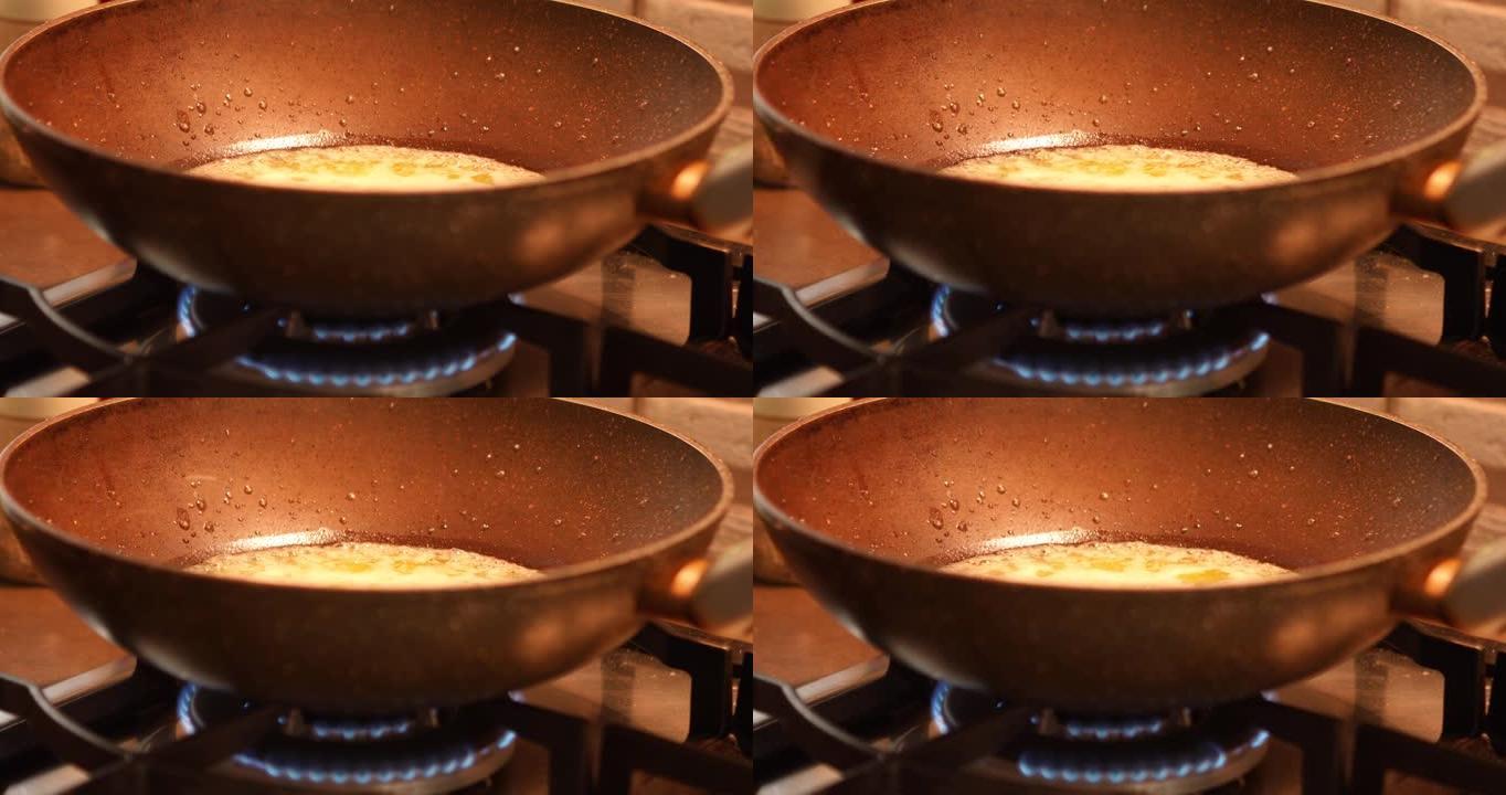 在煤气炉上的煎锅中煮沸并溅油