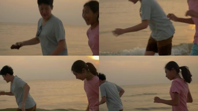亚洲儿童在沙滩上奔跑，具有日出背景，积极的生活方式理念。
