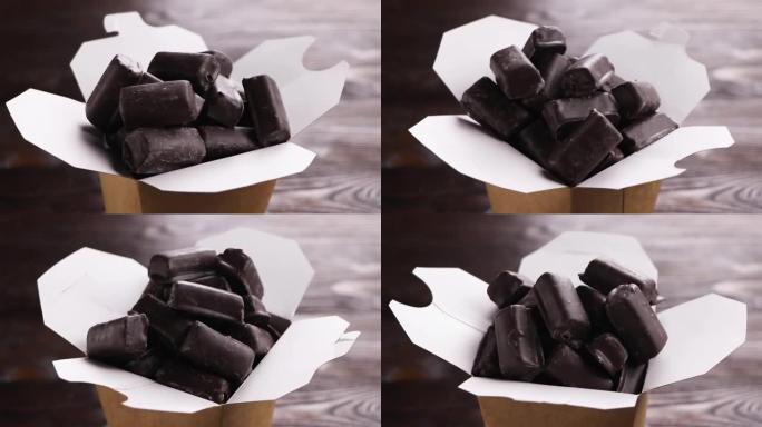 一盒手工巧克力。在纸盒中旋转巧克力糖果。木制背景。