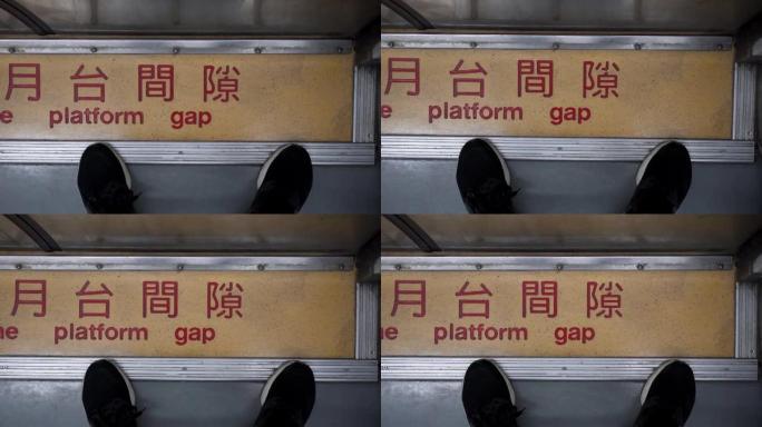 一个人站在火车车厢的门前。特写脚。中文意思是注意平台的差距。火车在行驶，相机摇晃。主题在右边。