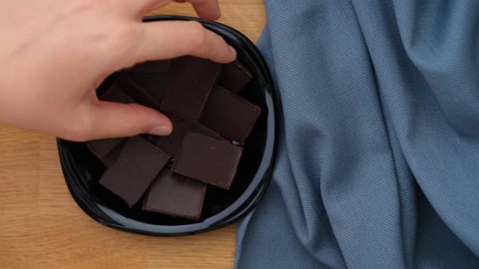 一名妇女从黑色盘子里捡起一块破碎的黑巧克力