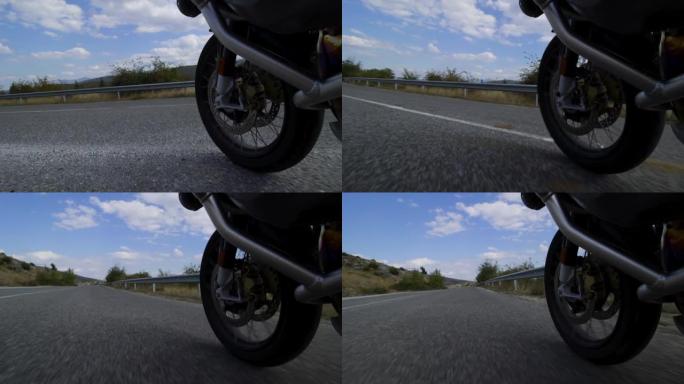 摩托车骑在自然界的道路上。在颠簸的沥青路面上关闭车轮。以100 fps记录。
