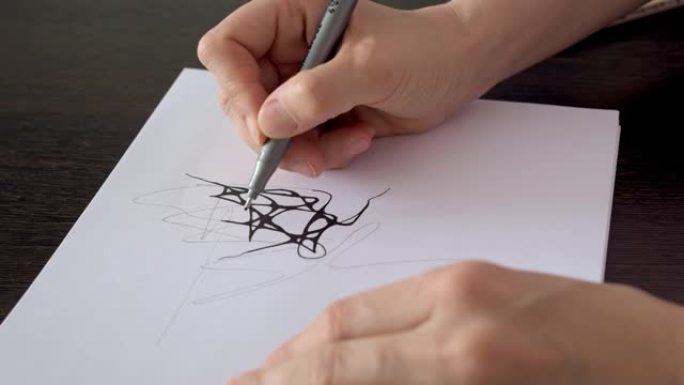 设计师使用黑色记号笔在纸上工作。艺术家在纸上画了一幅素描。手边的特写镜头，在纸上画线。神经造影和治疗