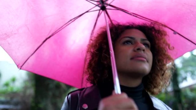 黑人妇女打开雨伞遮雨，巴西女孩在雨天散步