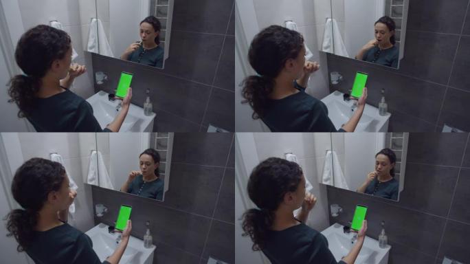黑人妇女在刷牙时看着带色度键的智能手机