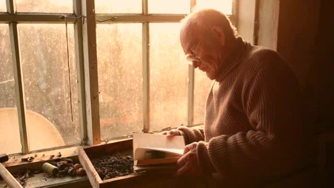 男人眼镜捡起灰尘中的旧书读在房子的窗户上