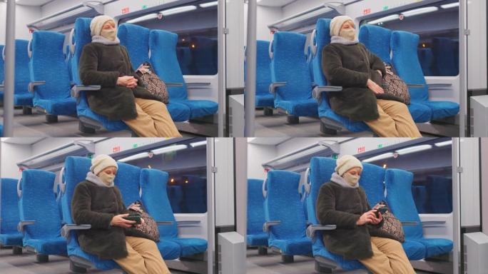 始终保持联系。戴着口罩的成熟女性在乘坐旅客列车时正在使用智能手机并检查社交媒体。