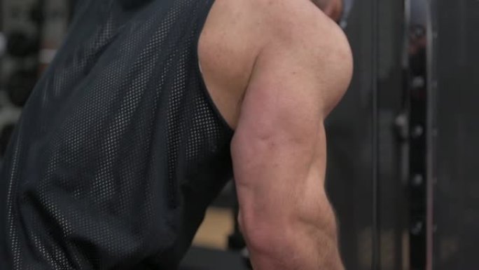强壮的健美男性在运动健身馆进行肱三头肌举重训练