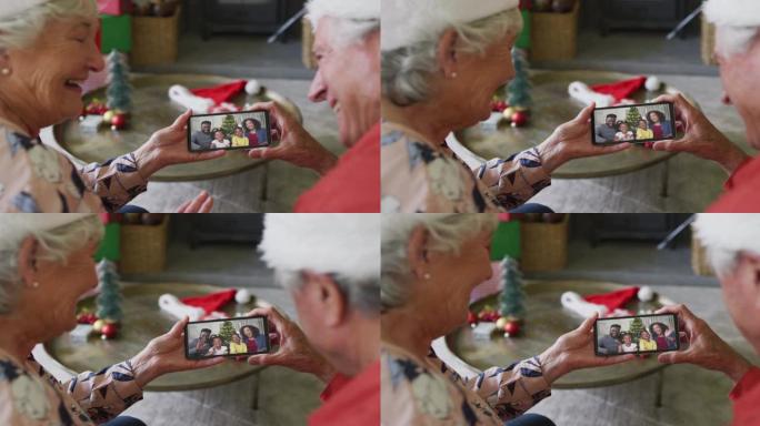 微笑的高加索高级夫妇使用智能手机与家人在屏幕上进行圣诞节视频通话