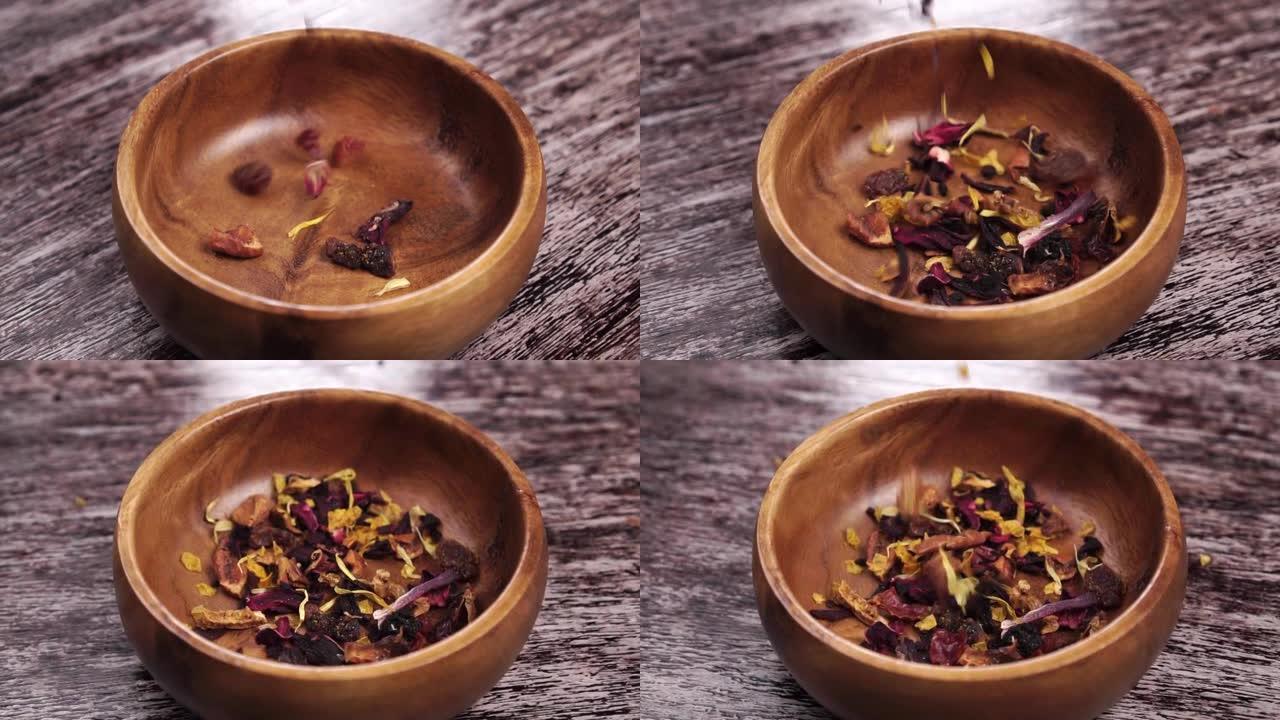 芳香的凉茶，带有干燥的花瓣和水果片。天然健康饮料配料落入乡村木碗