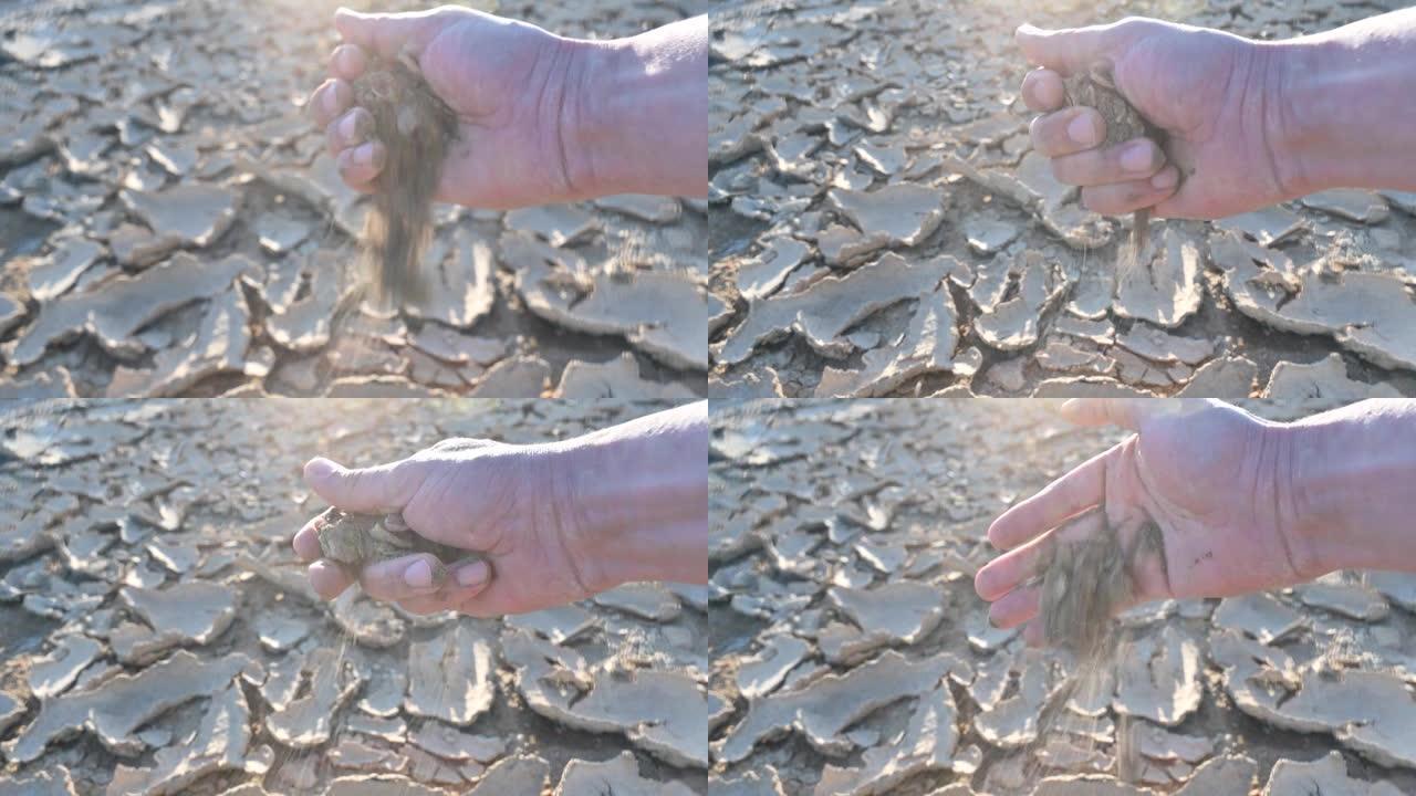男子手里拿着一些沙子在破裂的地面土壤上