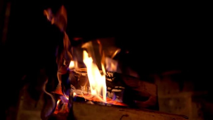 木制原木在黑暗中燃烧。壁炉里着火了。乡间别墅里温暖的火焰。家庭壁炉。特写。