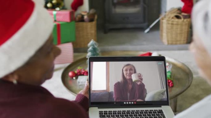 多元化的资深女性朋友使用笔记本电脑与屏幕上的幸福女人进行圣诞节视频通话