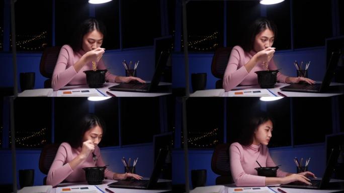 亚洲女商人在晚上的视频会议上在笔记本电脑上工作时吃方便面