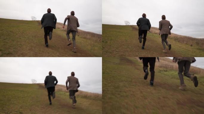 在多云的天气里，两名穿着经典夹克的男子从陡峭的山坡上跑到山顶