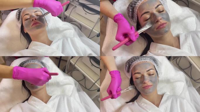 美容师在女人脸上涂面膜