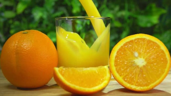 将新鲜的甜橙汁倒入大成熟橙子旁边的玻璃杯中