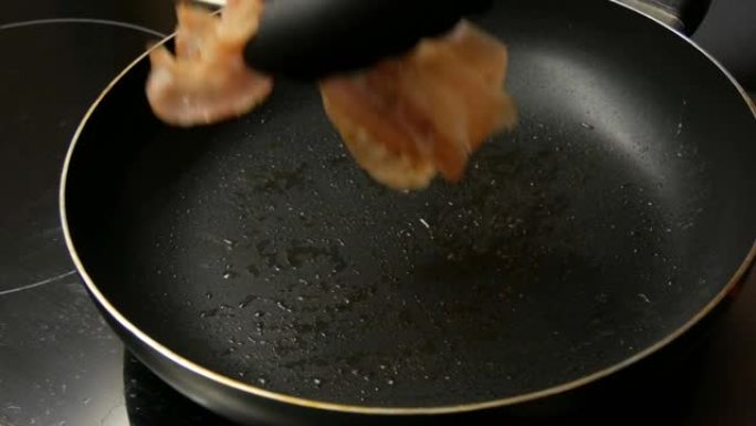 培根薄片用葵花籽油在热锅中油炸，并带有不粘涂层。厨师做饭做早餐，变成令人惊叹的脆皮培根