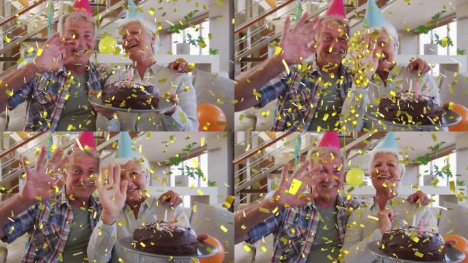 戴着派对帽的快乐高加索高级夫妇用蛋糕和金色五彩纸屑做生日视频通话
