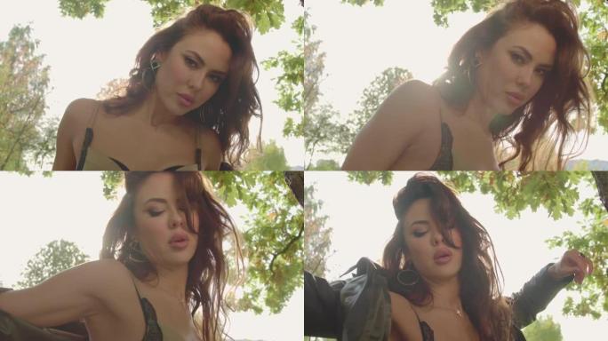 性感卷发黑发女人在阳光明媚的秋天在公园享受时光。美丽女人的脸在明亮的阳光下穿上夹克秋天户外。生活的快