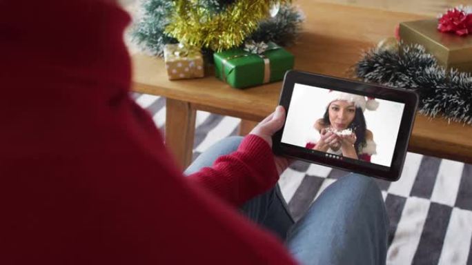 白人男子挥舞并使用平板电脑进行圣诞视频通话，屏幕上有微笑的女人