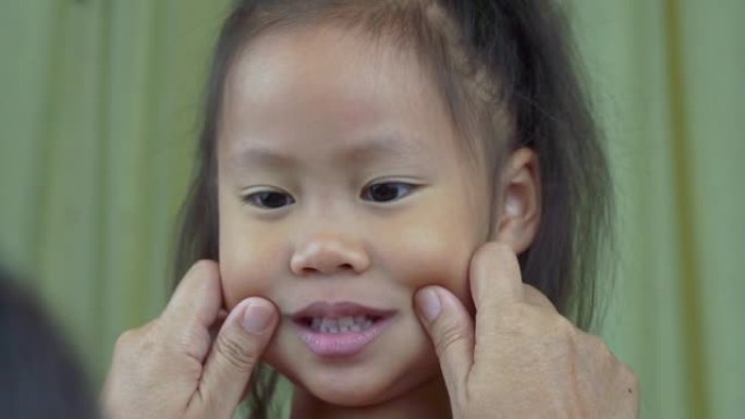 亚洲母子女孩玩捏脸颊，摸鼻子滑稽的脸。