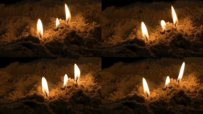 细长的黄色教堂蜡烛在沙子中燃烧