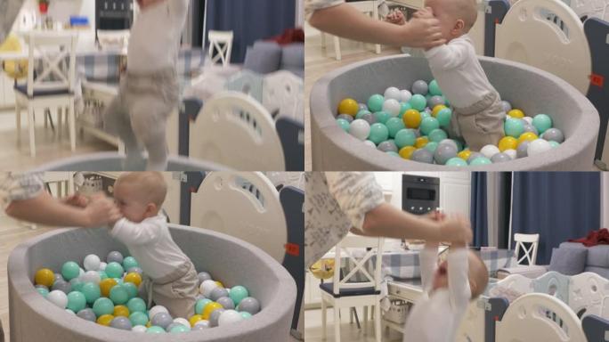 妈妈和快乐的宝宝在软球坑池玩五颜六色的球，9个月大的高加索孩子在儿童干池微笑，玩有趣的游戏。