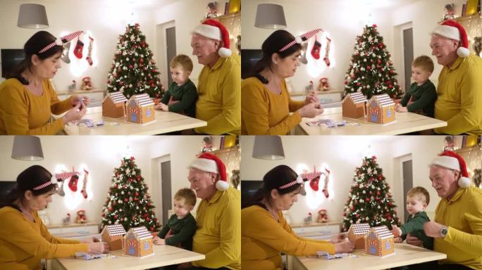 作为圣诞节的传统，快乐的高加索祖父母和孙子一起装饰姜饼屋