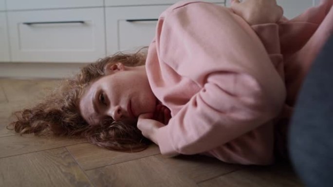 放大沮丧的年轻白人妇女躺在地板上的视频。用8k的红氦相机拍摄