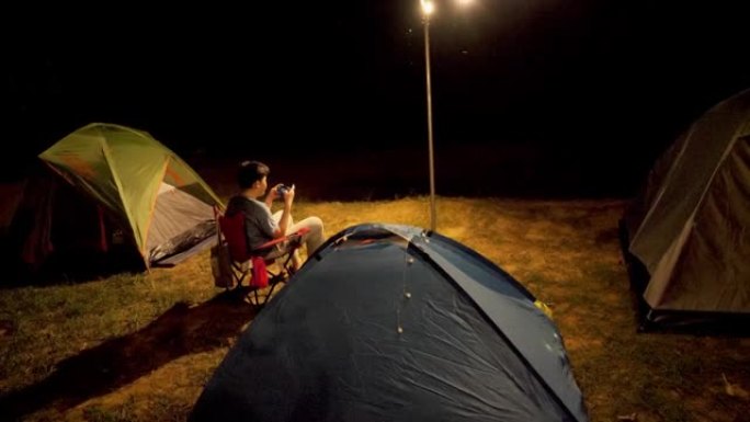 亚洲男孩在帐篷前玩手机游戏，与家人露营，生活方式理念。